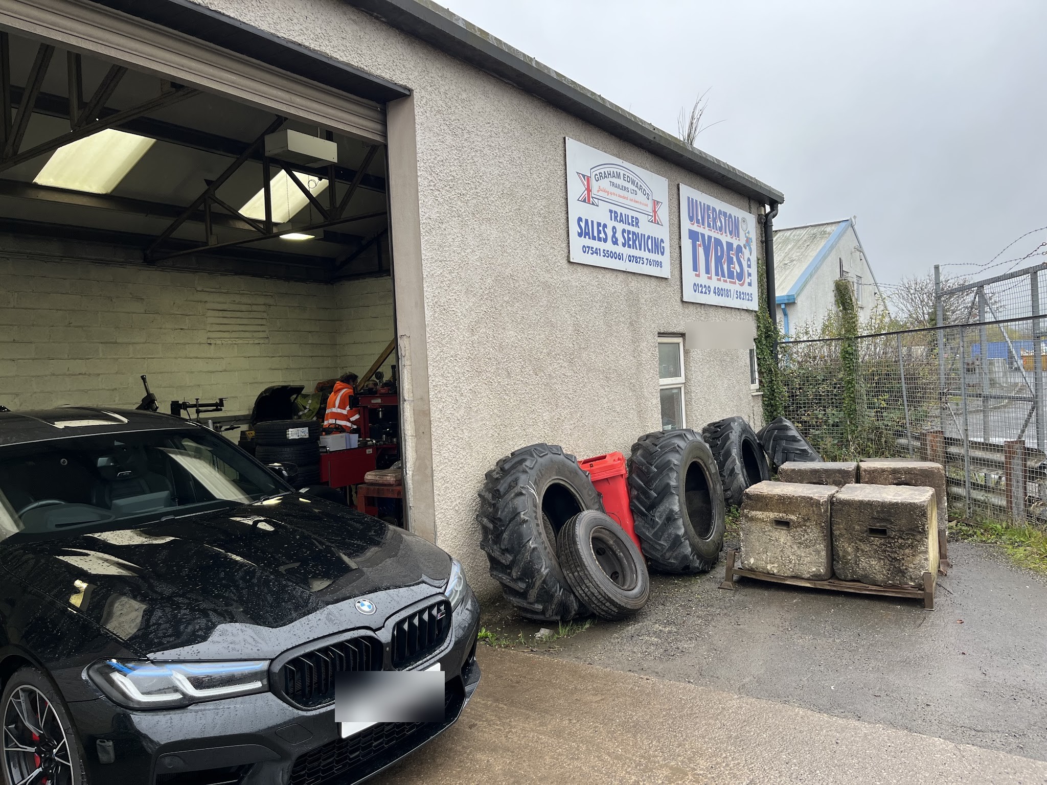 The Ulverston Tyres workshop on Cross Lane, door open, agricultural tyres stacked outside