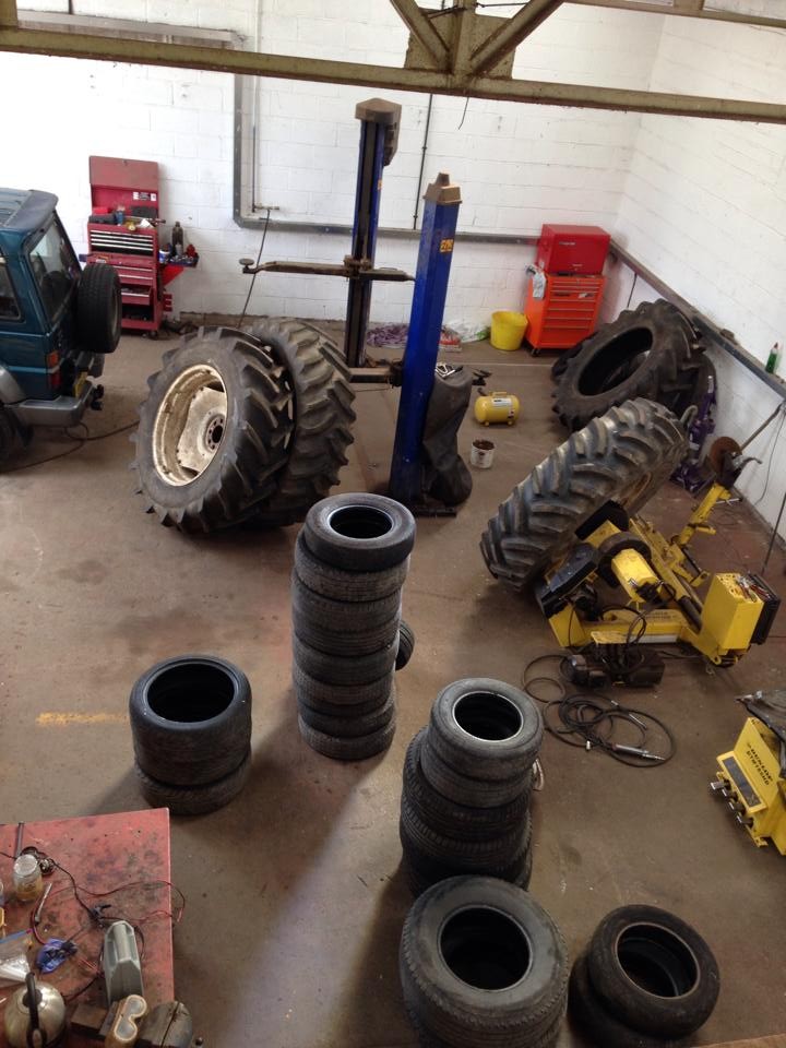Agricultural and car tyres on the workshop floor beside the tyre machine