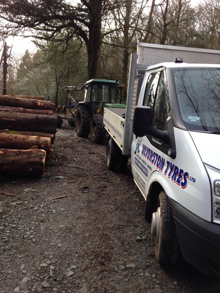 Ulverston Tyres van parked beside a tractor and a log stack on a woodland track