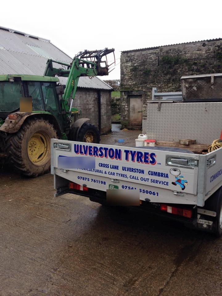 The back of the Ulverston Tyres pickup on a farm, tractor alongside